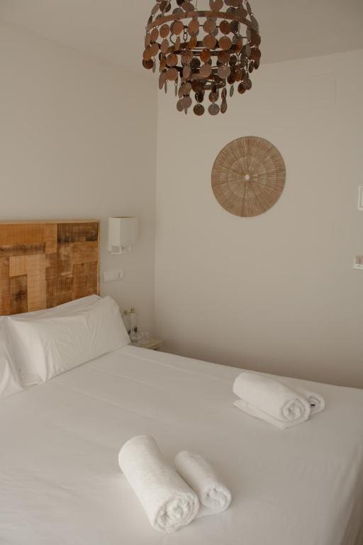 a bedroom with a white bed with two towels on it at Hostal La Torre Ibiza Cap Negret in San Antonio