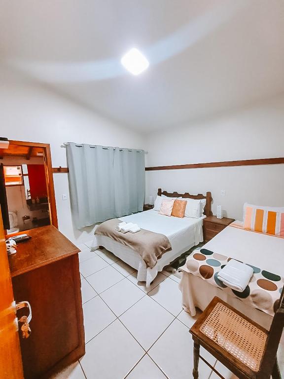 a room with two beds and a table and a mirror at Suítes da Penha in Capitólio