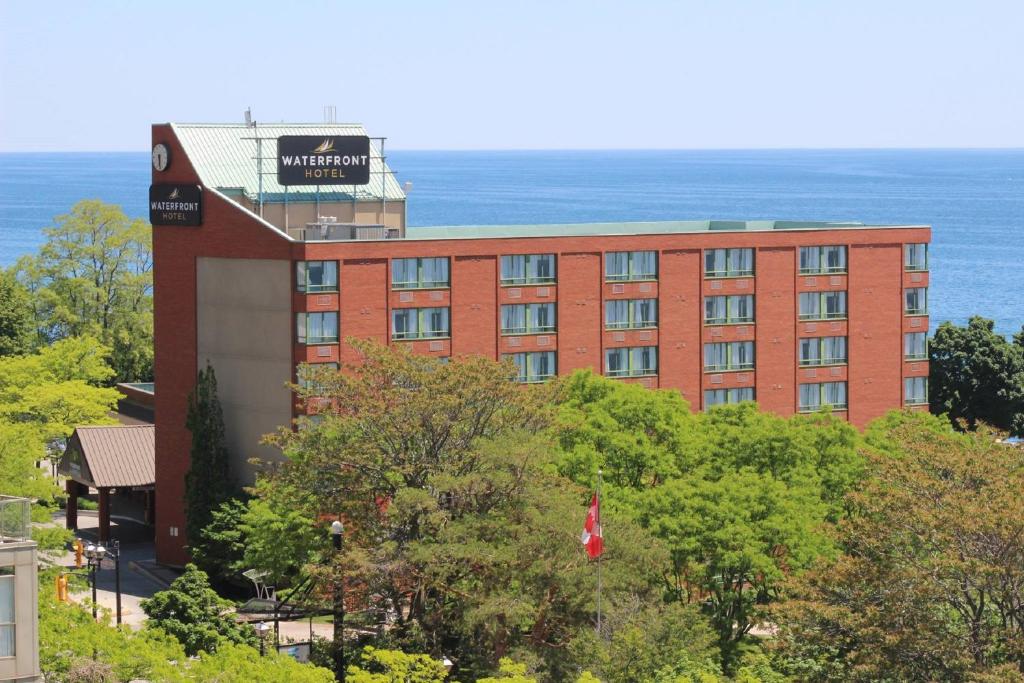 ein rotes Backsteingebäude mit dem Ozean im Hintergrund in der Unterkunft Waterfront Hotel Downtown Burlington in Burlington