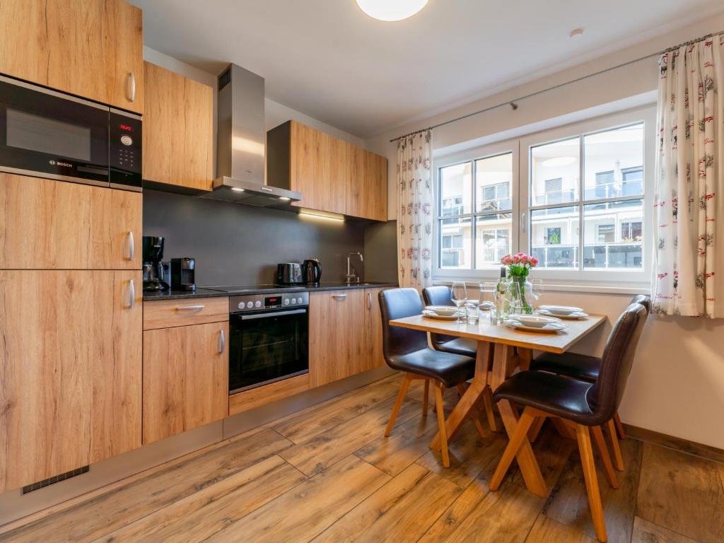 Una cocina con gabinetes de madera y una mesa con sillas. en Tauern Suites Mitterwirt TOP 215, en Piesendorf