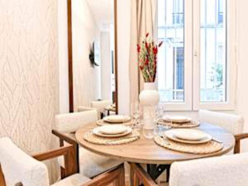 - une table à manger avec des assiettes et un vase dans l'établissement New flat with AC Porte Maillot Arc de Triomphe, à Paris