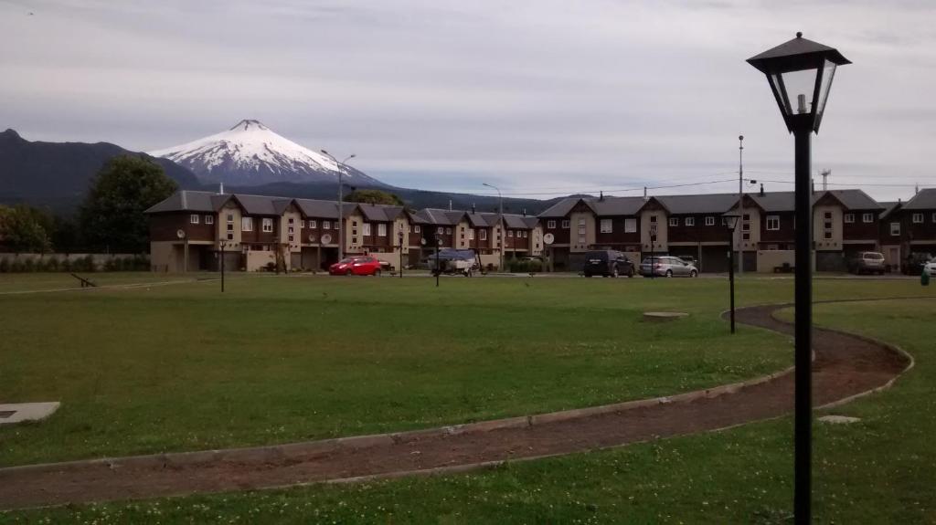 una montaña cubierta de nieve en la distancia con casas y luz de la calle en Casa Condominio Pucon, en Pucón