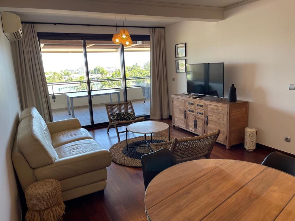 パペーテにあるTipanie- Great 1bedroom in PPT, AC w pool & open viewのソファ、テレビ、テーブルのあるリビングルーム