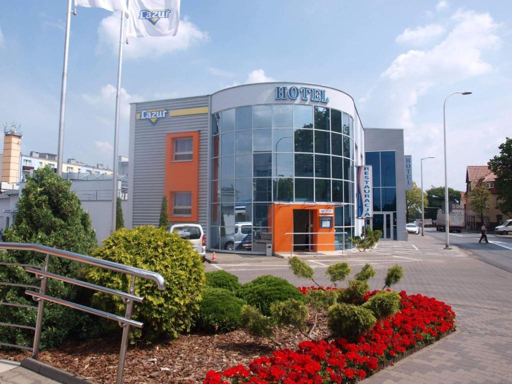 budynek honda z czerwonymi kwiatami przed nim w obiekcie Hotel Lazur SPA & Conference w Kaliszu