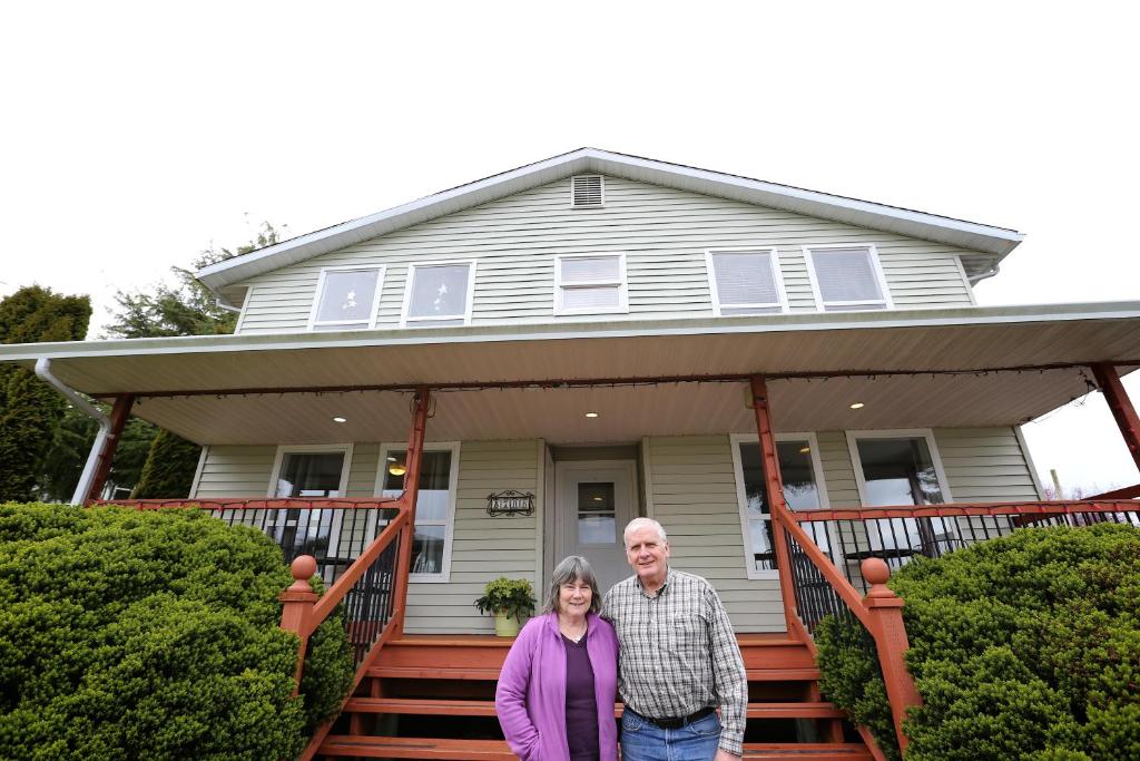 a man and woman standing on the front porch of a house at Telco House B&B in Port Hardy