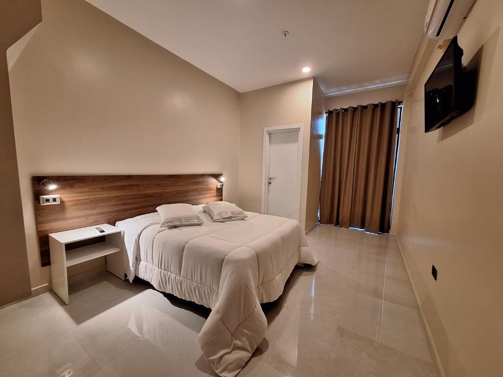 una camera d'albergo con un letto e una televisione di Hotel Brasil a Caazapa New