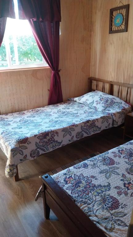 due letti in una stanza con una finestra di Cabañas Kapüra a Hornopiren