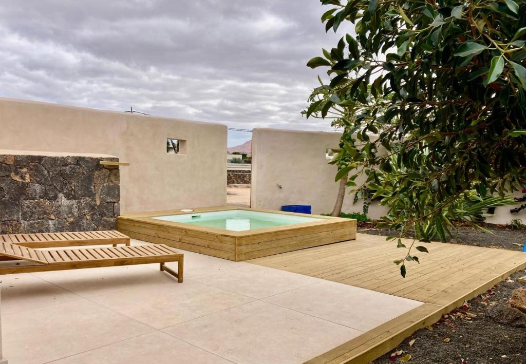 un patio trasero con una piscina, un banco y una casa en Villa Lavayarena private pool in Lajares, en La Oliva