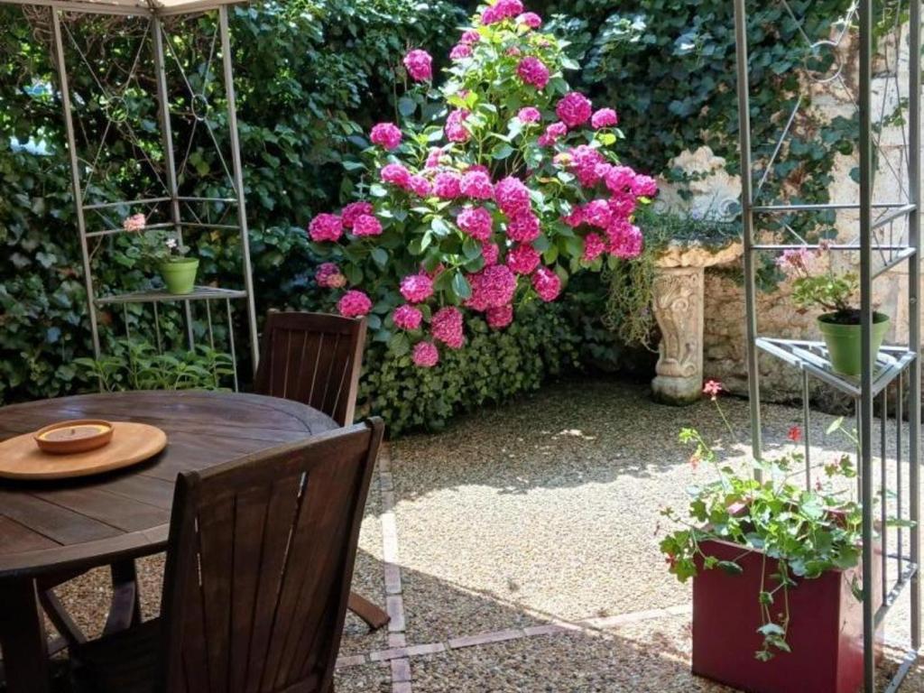 a table and chairs in a garden with pink flowers at Maison de charme à Brantôme, animaux admis, parking inclus - FR-1-616-461 in Brantôme