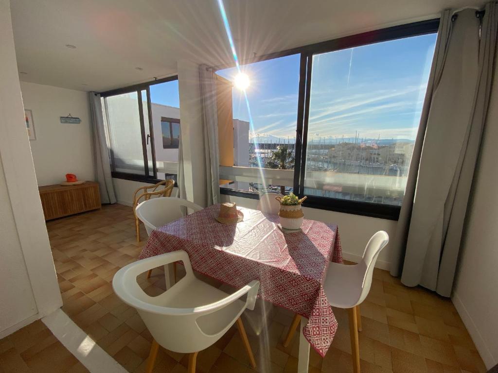 une salle à manger avec une table et des chaises et une grande fenêtre dans l'établissement Port Leucate: T2 Climatisé, WIFI, Animaux ok, Parking Sécurisé - FR-1-798-52, à Leucate