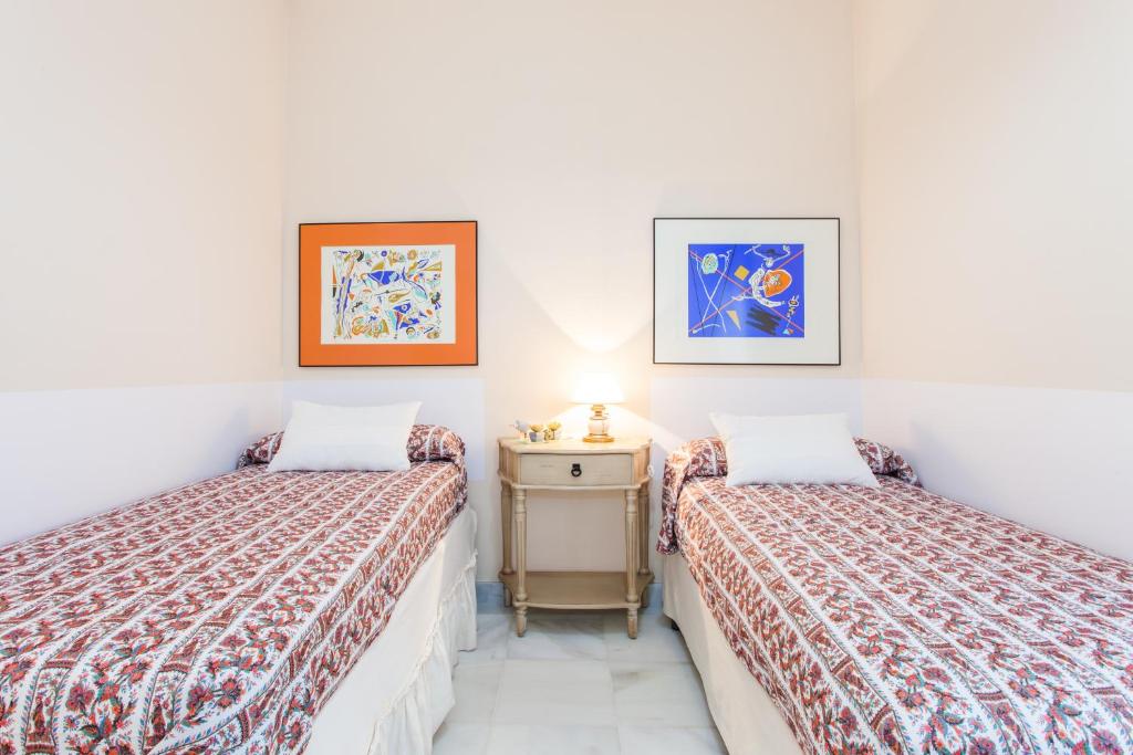a bedroom with two beds and a table with a lamp at Casa Singular , parking gratis in Jerez de la Frontera