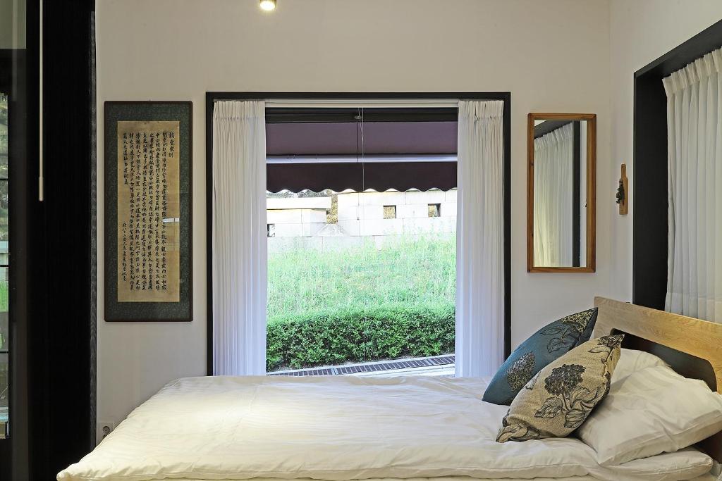 ein Schlafzimmer mit einem Bett und einem großen Fenster in der Unterkunft Jian Hanok in Seoul