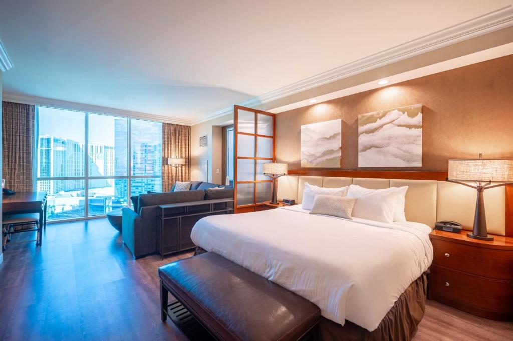 a hotel room with a large bed and a couch at No Resort Fee Strip View Suite+ Free Valet + Pool in Las Vegas