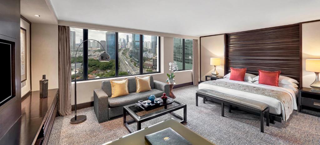 a bedroom with a bed and a couch and a tv at Mandarin Oriental, Jakarta in Jakarta
