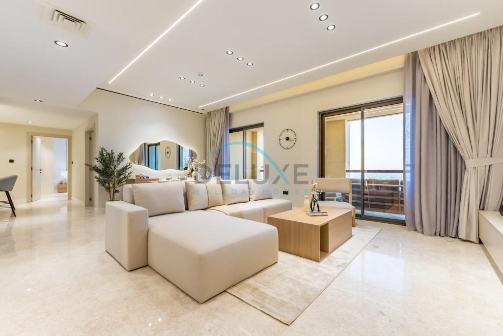 a living room with a white couch and a table at Sea and Palm Jumeirah Views Just Steps from the Beach 2BR, Sadaf 6 , JBR by Deluxe Holiday Homes in Dubai