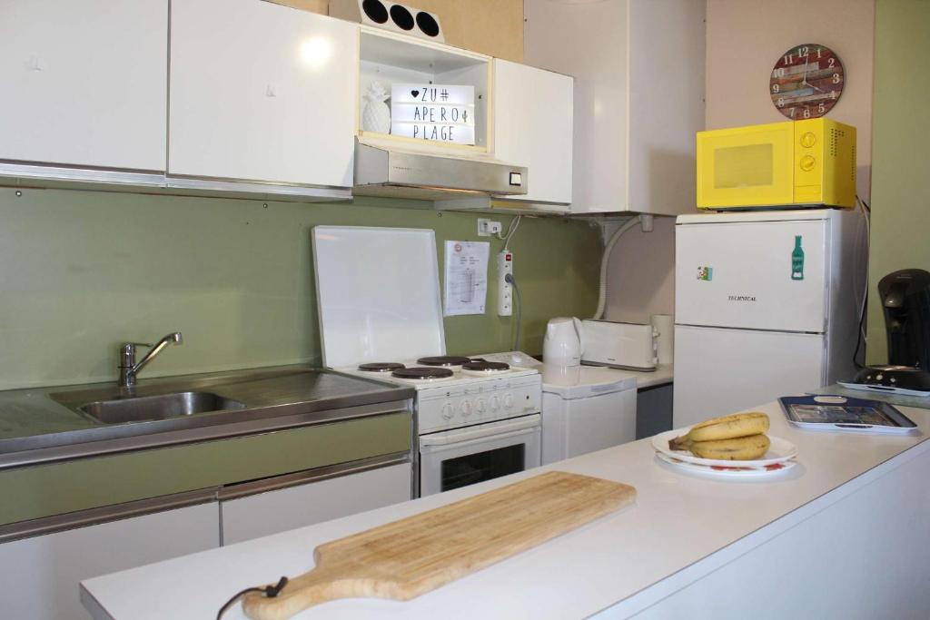 une cuisine équipée d'appareils blancs et d'une planche à découper sur un comptoir dans l'établissement Appartement 2 pièces PORT LA NOUVELLE PN210-010, à Port-la-Nouvelle