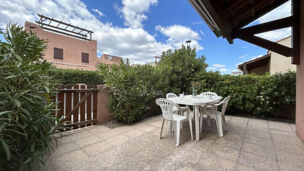 une table blanche et des chaises sur une terrasse dans l'établissement Maison 2 pièces mezzanine - Gruissan Ayguades AY060-135, à Vires
