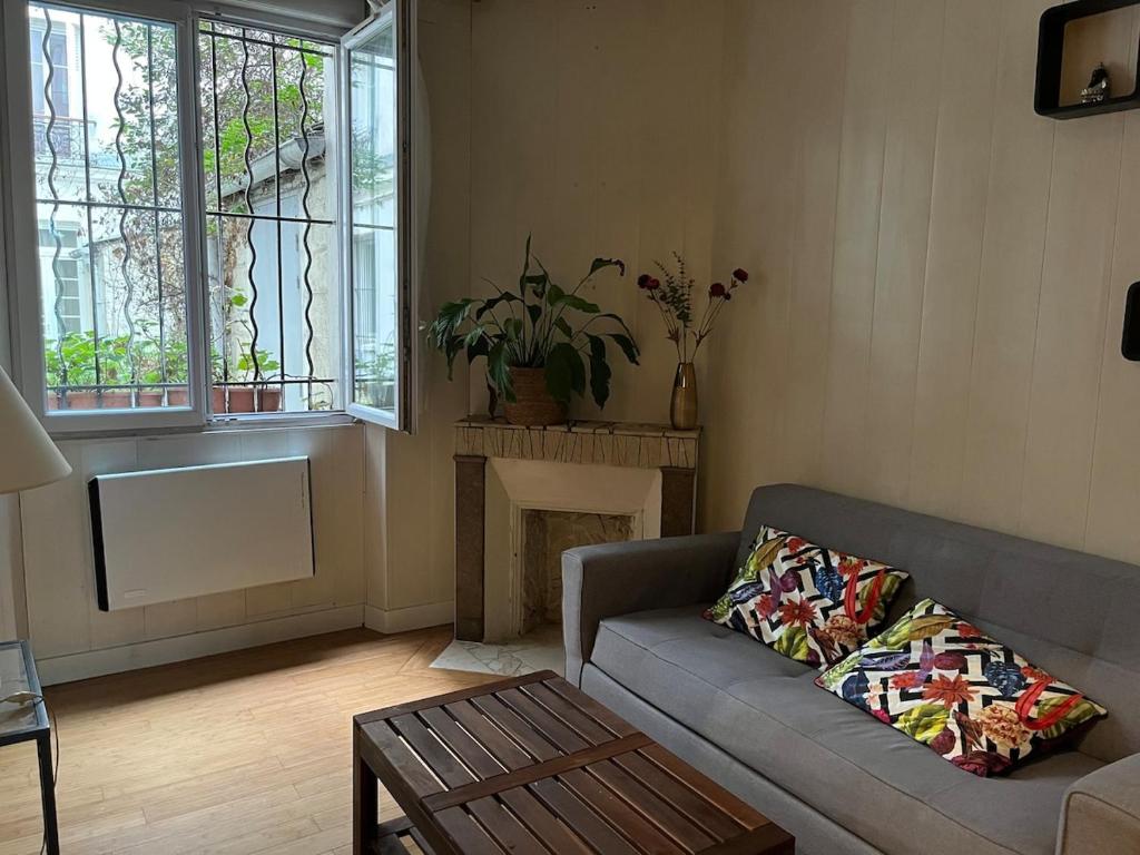 un salon avec un canapé et une cheminée dans l'établissement Appartement charmant à Paris 20 eme, à Paris
