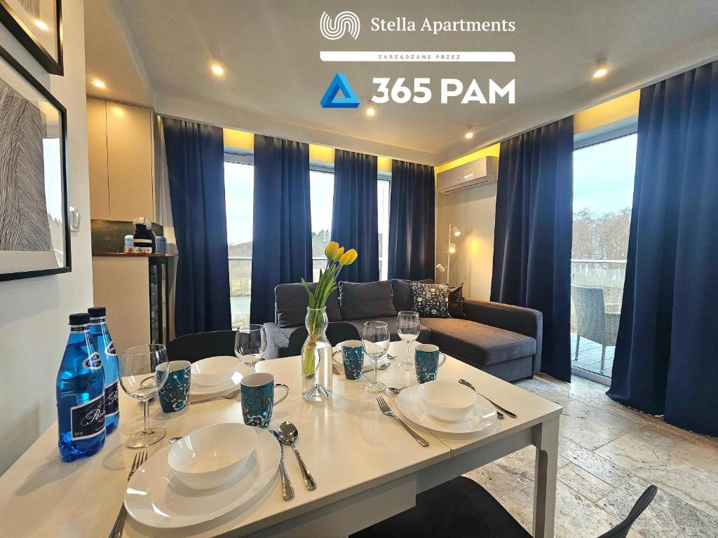 a table with plates and glasses on it in a living room at 365PAM - Apartament Bliżej Morza w Gąskach in Gąski