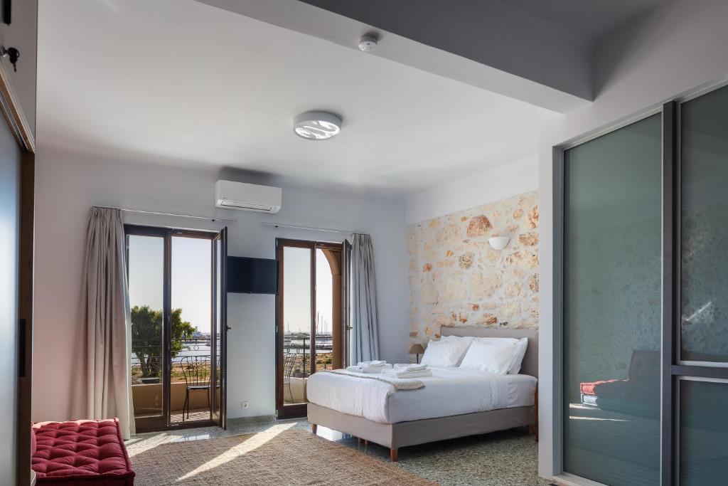 a bedroom with a white bed and a balcony at Chryssi 01, Stylish Seaside Spot in the Heart of Rethymno in Rethymno Town