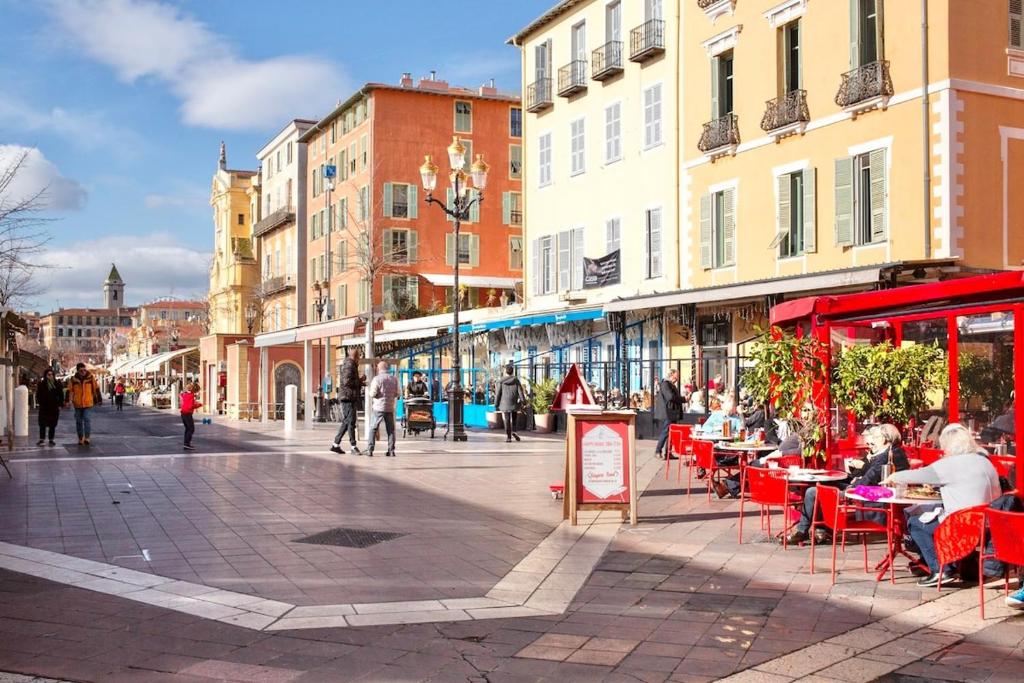 eine Stadtstraße mit Leuten, die an Tischen und Gebäuden sitzen in der Unterkunft Proche du Cours Saleya et de la plage, dans le vieux Nice, spacieux et climatisé in Nizza