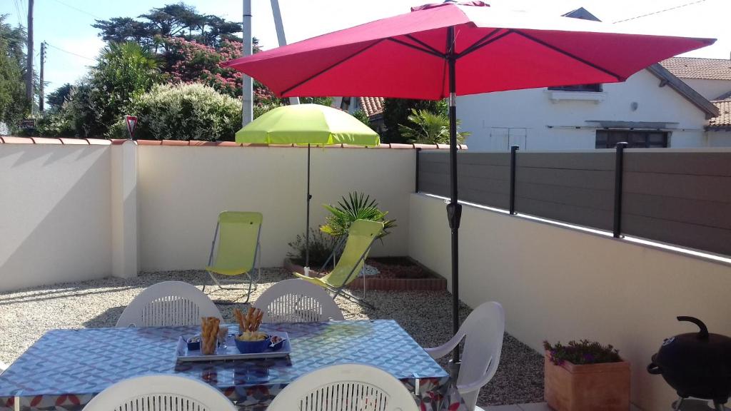d'une terrasse avec une table et un parasol rouge. dans l'établissement 36 - Maison intime 4p, plage à pied, à Pornic