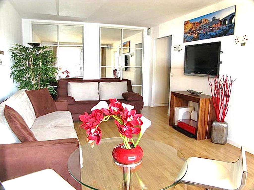 een woonkamer met een bank en een tafel met bloemen bij LE BELLEVUE appartement GRAND CONFORT à Cassis in Cassis