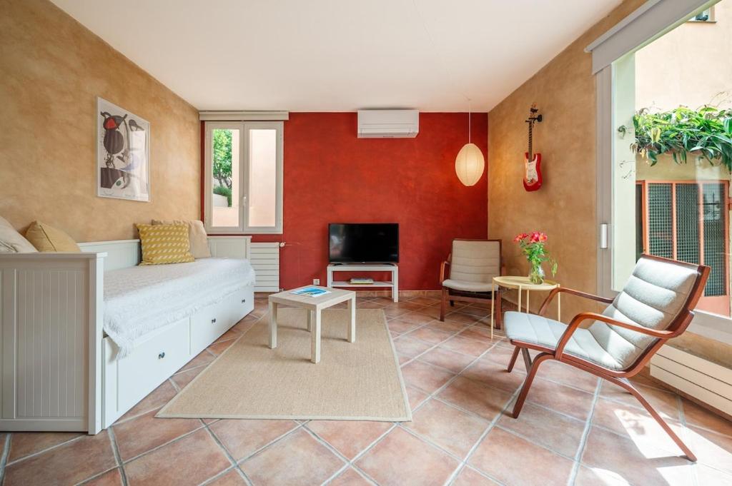 - un salon avec un mur rouge dans l'établissement Val de Menton, Charmant 3 pièces atypique, jardin et terrasse à 7 minutes à pied du centre ville, à Menton