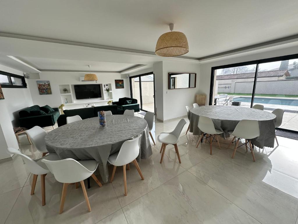 a living room with two tables and chairs and a couch at Maison 70 avec 8 chambres lechaffardcom in Satolas-et-Bonce
