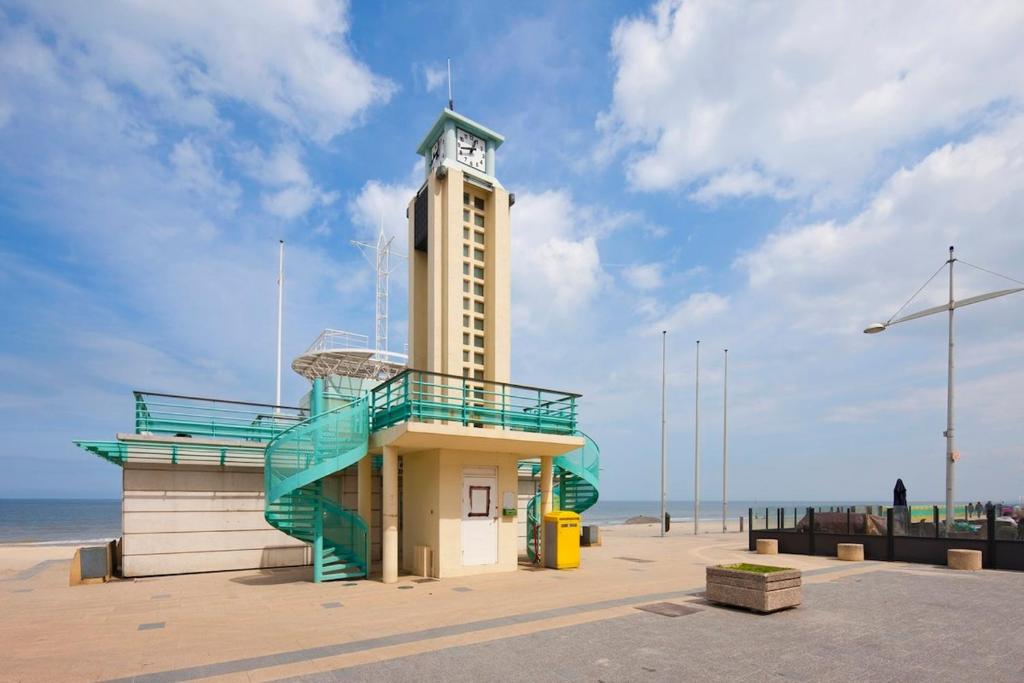 Un edificio con una torre de reloj en la playa. en Evasion Côtière,Studio à 2 pas de la plage, en Dunkerque