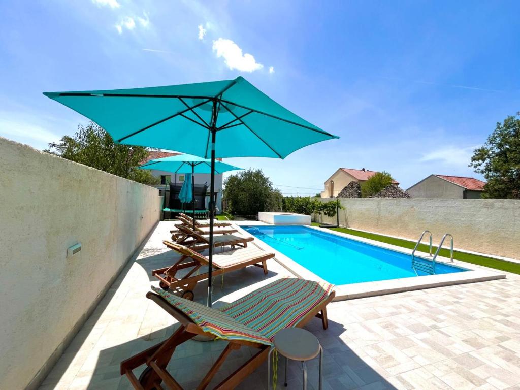 una piscina con due lettini e un ombrellone blu di Stone & Sun Retreat with Private Pool a Rupalj