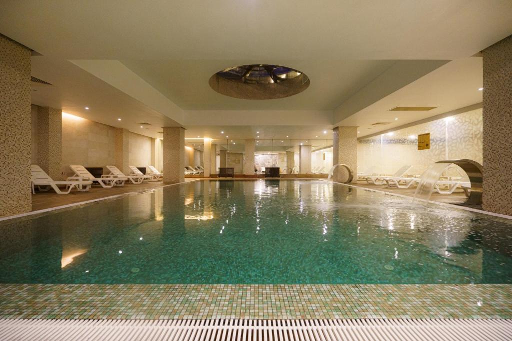 a swimming pool in a hotel with chairs and a ceiling at Boyalik Beach Hotel & Spa Cesme in Çeşme