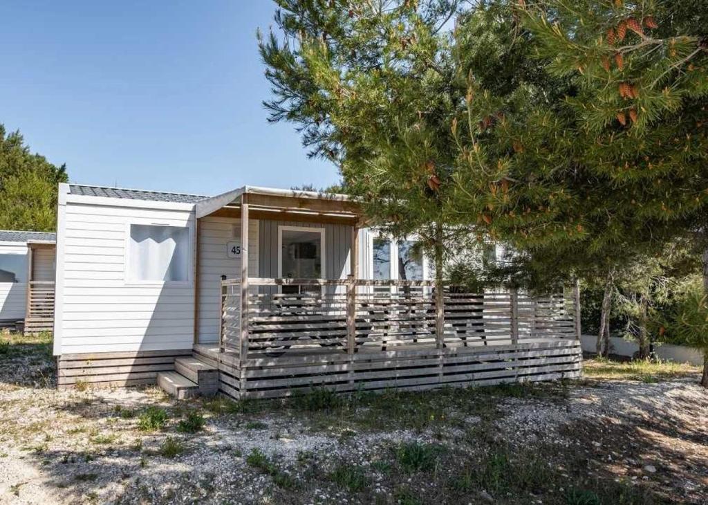 un petit hangar blanc avec une véranda à côté d'un arbre dans l'établissement Camping 4 étoiles - Parc aquatique - ef0bdc, à Martigues