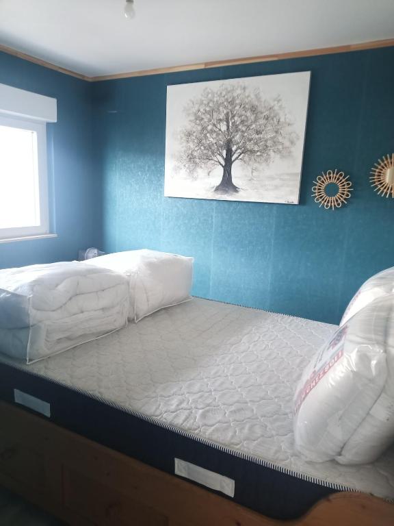 un grand lit dans une chambre avec un arbre sur le mur dans l'établissement Clair de lune, à Murat-le-Quaire