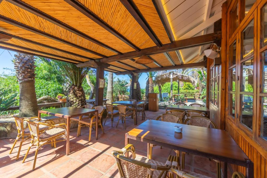 an outdoor patio with tables and chairs and windows at Hurricane Beach Hotel in Tarifa
