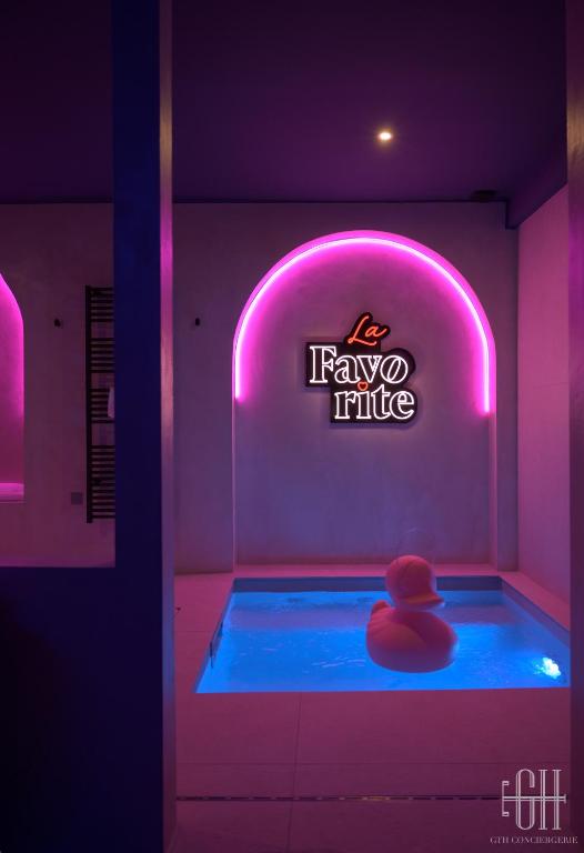 - un bain à remous dans une pièce avec un panneau de néon dans l'établissement La Favorite - Love-Room Sensuelle, à Amboise