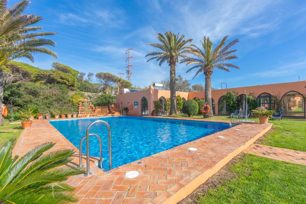a swimming pool in a yard with palm trees at Hurricane Beach Hotel in Tarifa