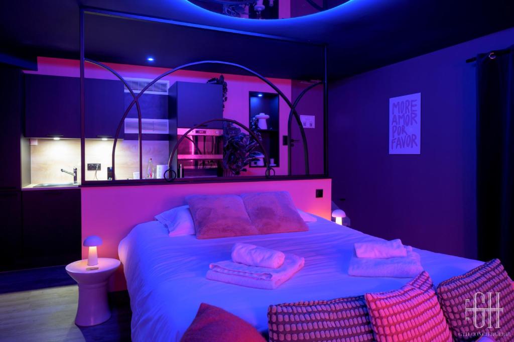 ein Schlafzimmer mit einem großen Bett mit rosafarbener Beleuchtung in der Unterkunft La Favorite - Love-Room Sensuelle in Amboise