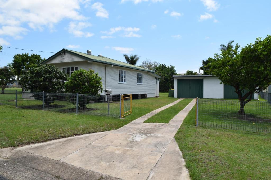 a white house with a fence in front of it at Tin Can Bay's Sleepy Lagoon Motel in Tin Can Bay