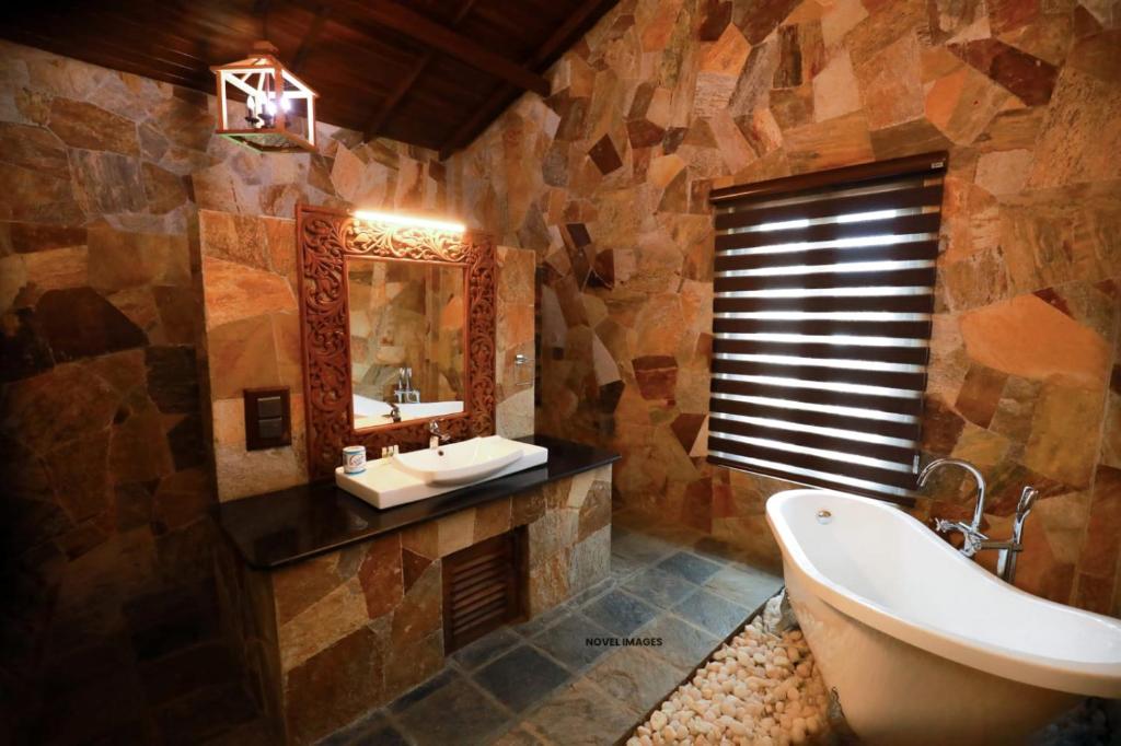 Florain Otium Talpe - 3 Bedroom Oceanfront Villa في يوناواتونا: حمام مع حوض استحمام ومغسلة ومرآة