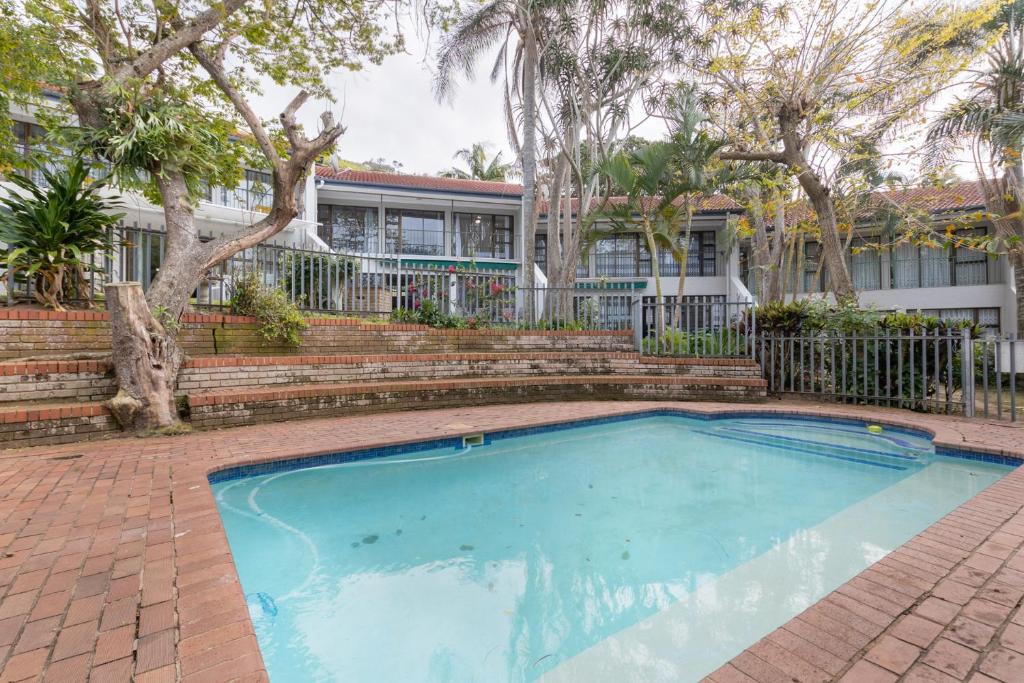 a swimming pool in front of a house with trees at Unit 4 Springvale in Zinkwazi Beach