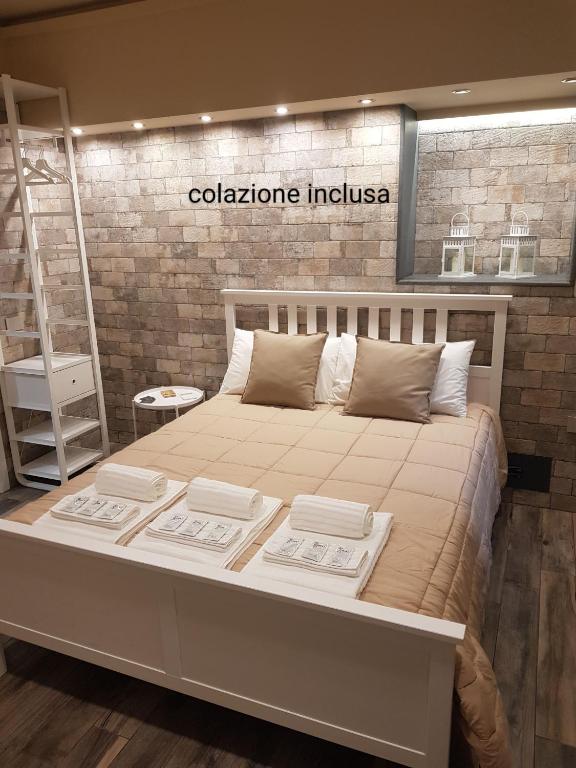 a large bed in a room with a brick wall at VENTIMIGLIA SUITE & WINE in Catania