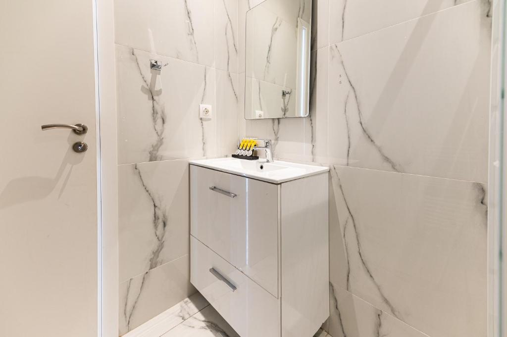biała łazienka z umywalką i lustrem w obiekcie Stylish spacious apartment in Palaio Faliro (C1) w Atenach
