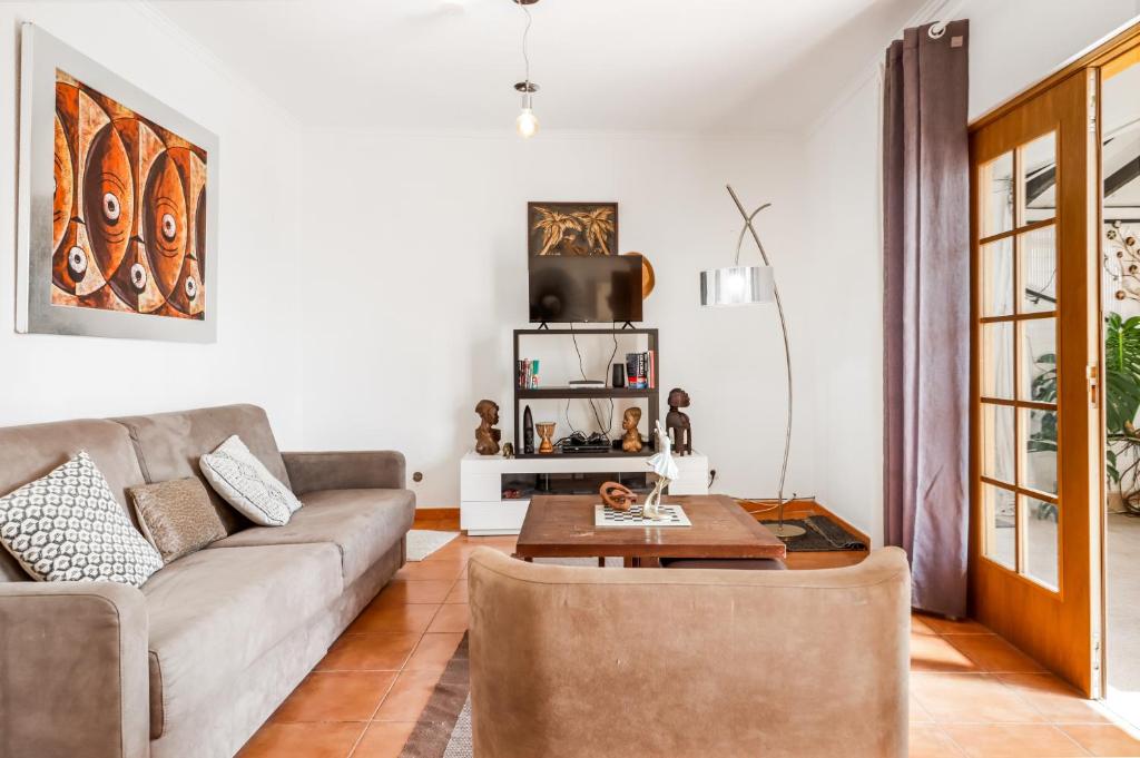 a living room with a couch and a table at Saude Beach House in Costa da Caparica
