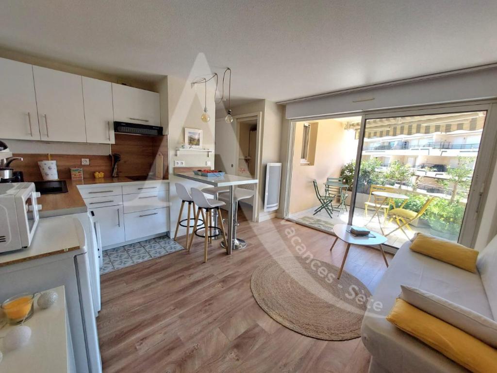 une cuisine et un salon avec une table et des chaises dans l'établissement T2 sur zone pietonne, a quelques pas des plages, à Sète