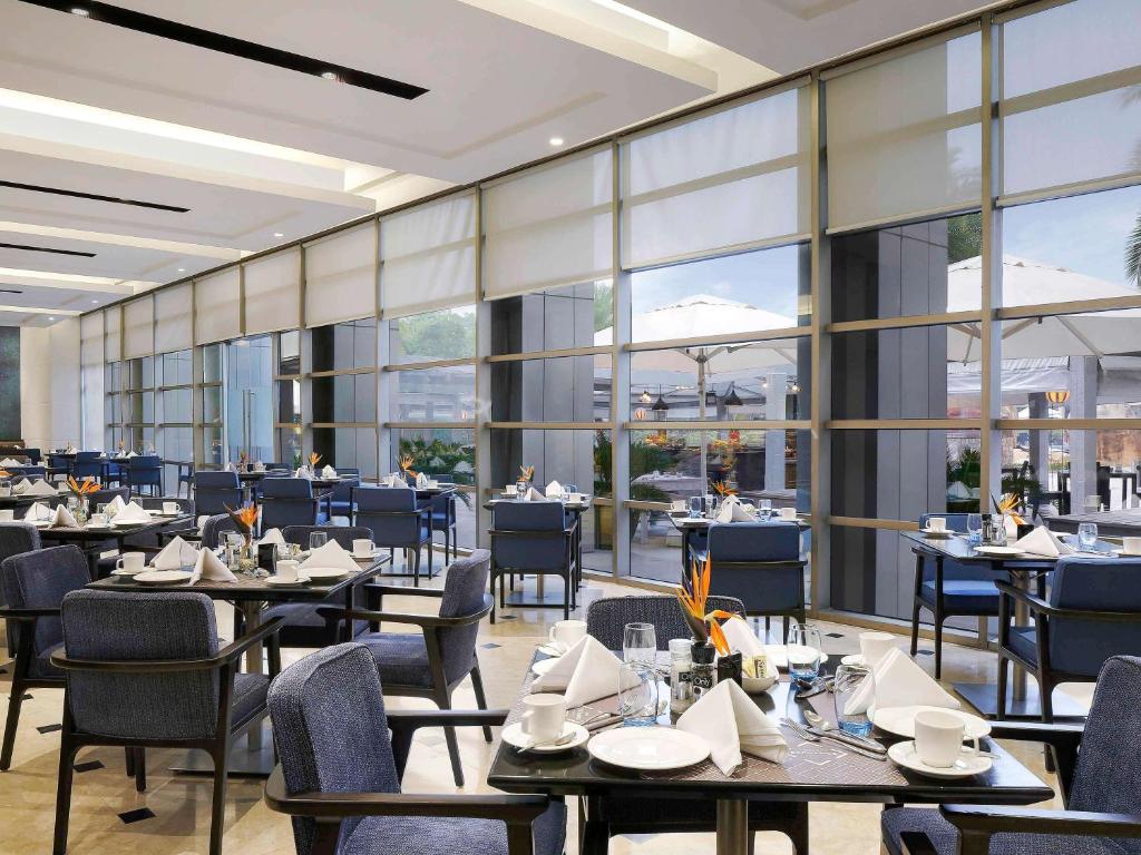 a restaurant with tables and chairs and large windows at Novotel Hyderabad Convention Centre in Hyderabad