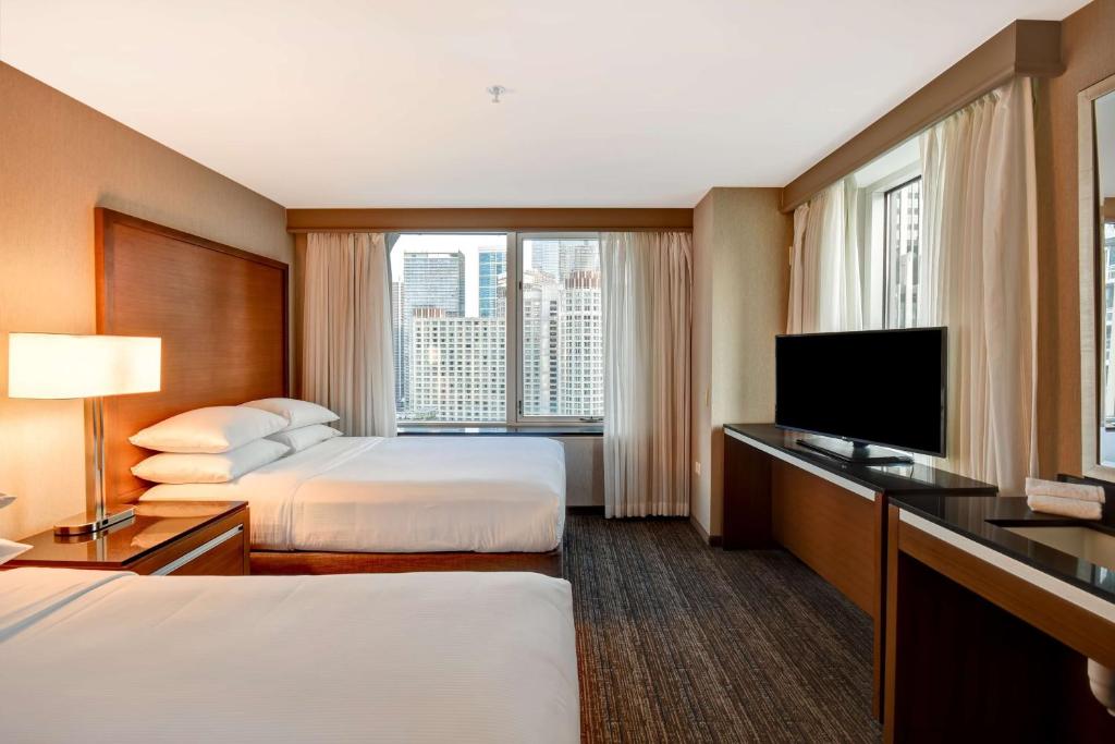 a hotel room with two beds and a flat screen tv at Embassy Suites by Hilton Chicago Downtown Magnificent Mile in Chicago