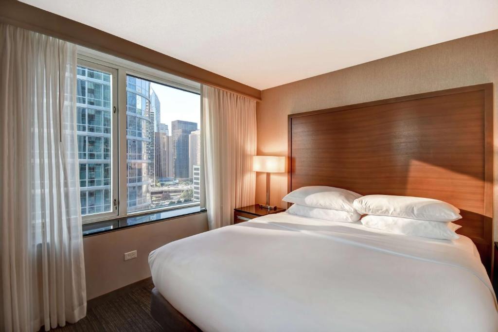 a bedroom with a large bed with a large window at Embassy Suites by Hilton Chicago Downtown Magnificent Mile in Chicago