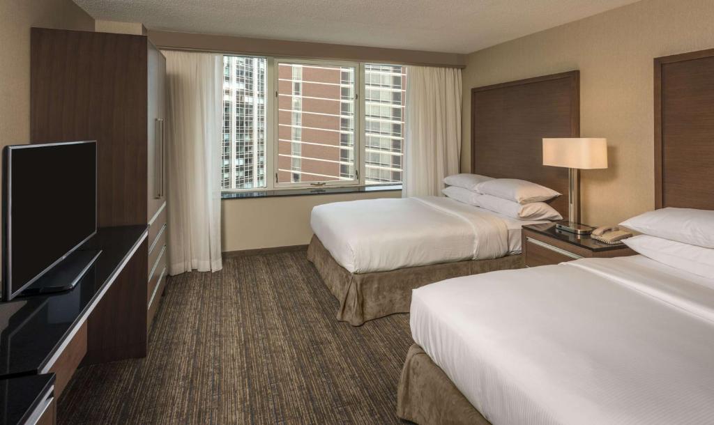 a hotel room with two beds and a flat screen tv at Embassy Suites by Hilton Chicago Downtown Magnificent Mile in Chicago