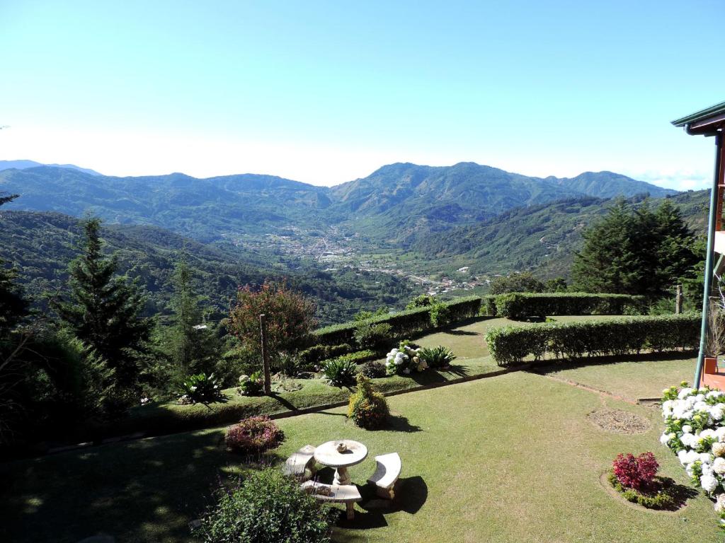 un jardín con mesas y sillas y montañas al fondo en Quinta Galeon Lodge, en Santa María